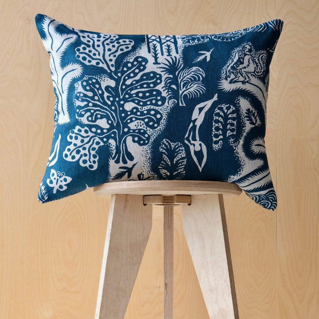 Blue and white patterned cushion on a wooden stool against a wooden ply wall