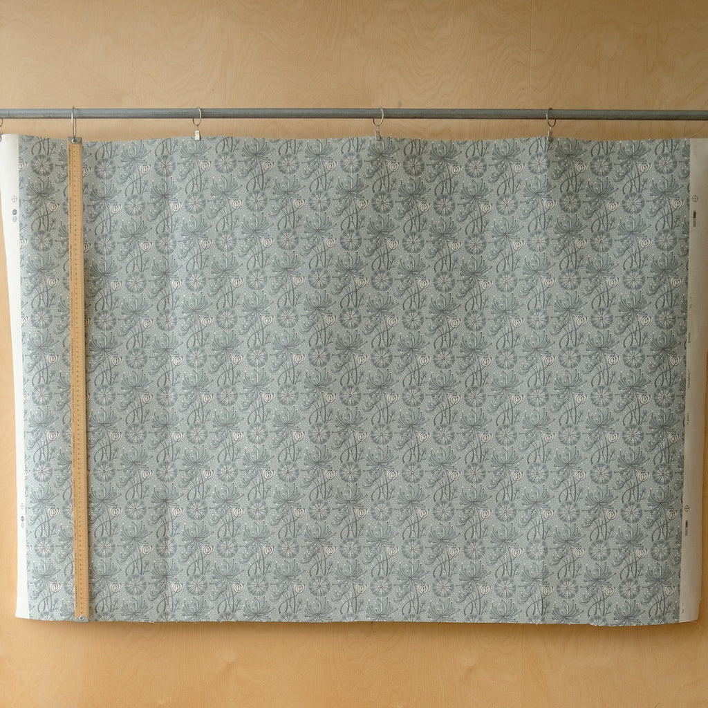 Patterned grey and white fabric on a rod against a wooden ply wall 