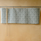 grey white fabric with seedhead patterns in front of plywood wall 