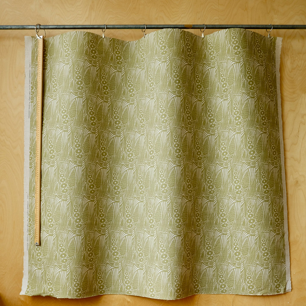 A fabric curtain with a repeating leaf pattern in olive green