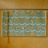Decorative fabric with intricate patterns hanging on a rod against a wooden wall.