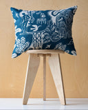 Decorative cushion with blue and white pattern on a wooden stool against a wooden wall.