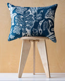 Blue and white patterned cushion on a wooden stool against a wooden ply wall