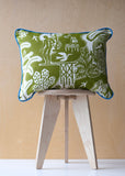 Printed fabric design of a cushion in green and white patterned fabric on a small wooden stool against a beige background