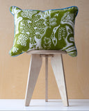 Printed fabric design of a cushion in green and white patterned fabric on a small wooden stool against a beige background