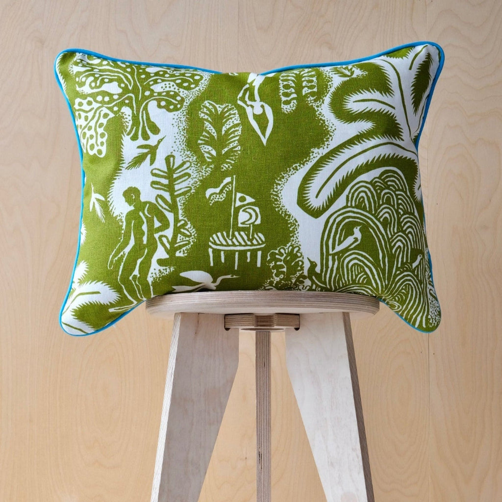 Green patterned cushion with turquoise trim on a wooden stool against a light wood panel background
