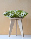 Wooden stool with a green and white patterned cushion on a light wooden background
