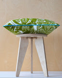 Green and white cushion with turquoise trim on a wooden stool with wood background