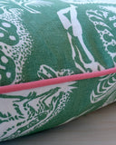 Green pillow with white patterns on a beige background with pink trim detail 