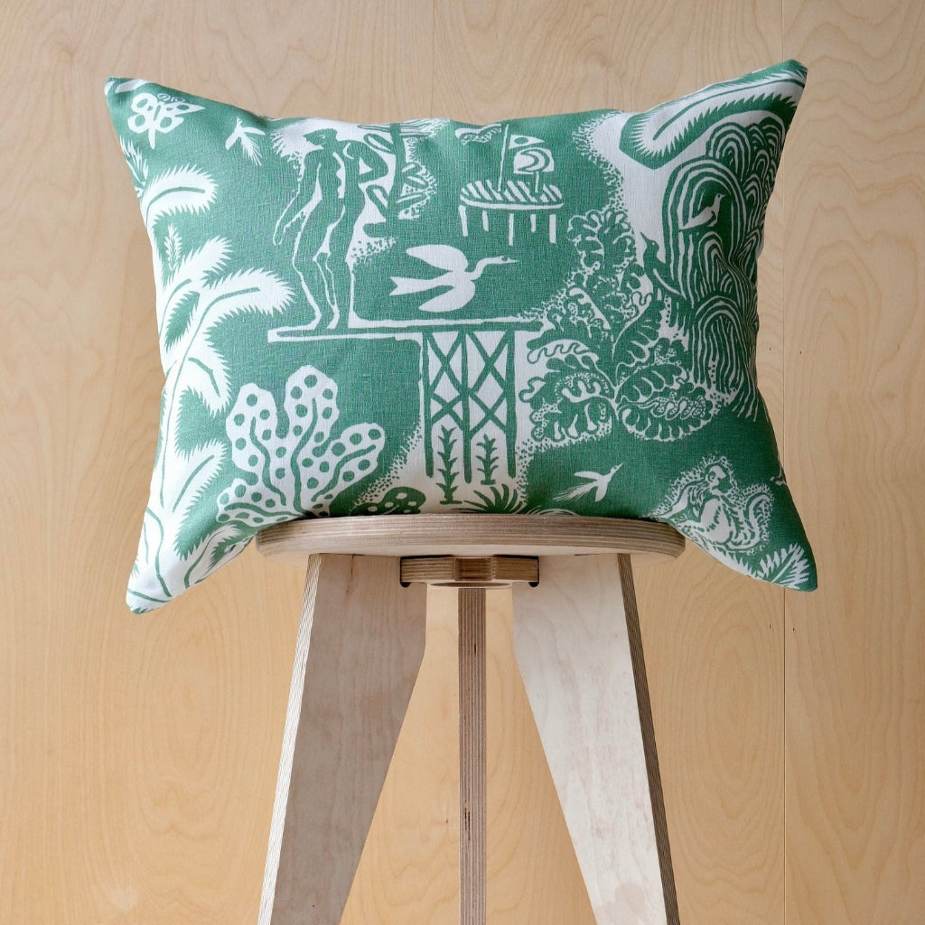 Decorative cushion with green and white pattern on a wooden stool against a wooden background