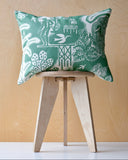 Decorative cushion with green and white pattern on a wooden stool against a wooden background