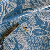 Blue and white patterned fabric with hares and birds scissors and pins on top
