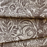 Close-up of brown printed fabric with plant and animal patterns. 