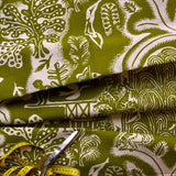 Green and white patterned fabric with scissors and a measuring tape on top